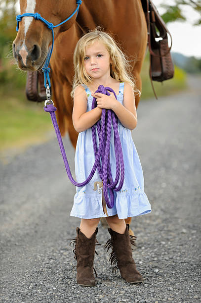 маленькая девочка с большой лошади в сапоги платье и синий - horse child pony little girls стоковые фото и изображения