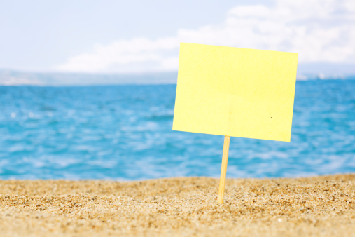Blank yellow board on sandy beach,  sky and sea in background