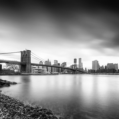 Black and white image of Brooklyn bridge with Manhattan in background. 