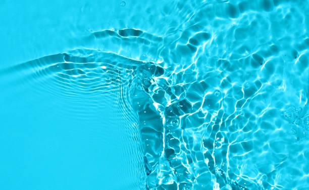 istock Summer nature banner. Defocused  liquid colored clear water surface texture with splashes bubblesWater waves in sunlight background. 1553964633