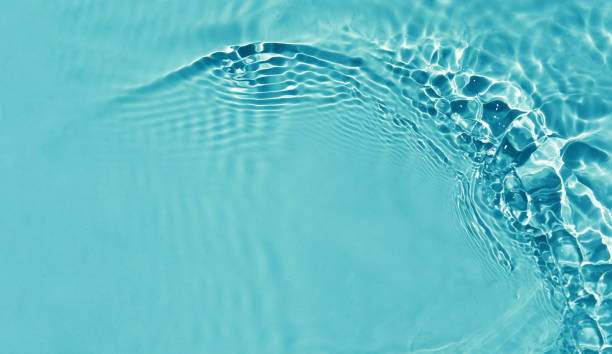 istock Summer nature banner. Defocused  liquid colored clear water surface texture with splashes bubblesWater waves in sunlight background. 1553964635