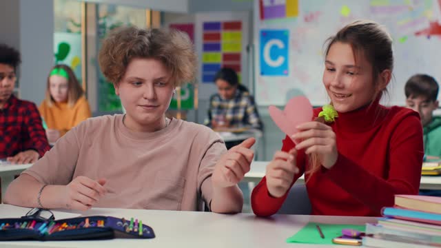 Teen boy give pink heart love note to classmate
