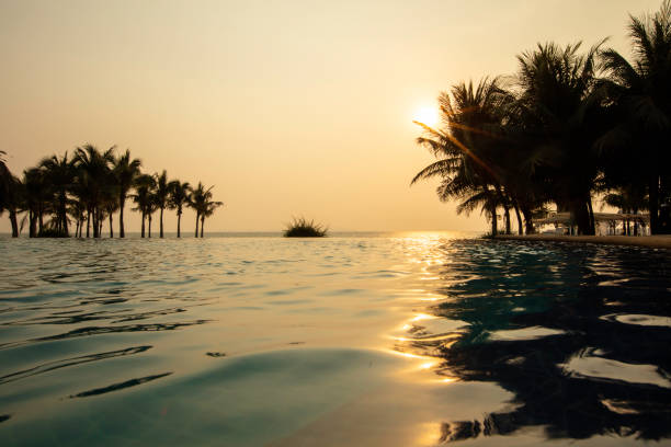 istock Modern swimming pools the on beach with sunset or sunrise 1554010461