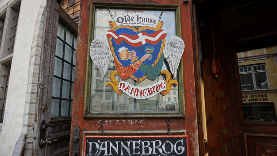 Colorful and picturesque signboard at the entrance to the bar in Tallinn. Images of cups of beer and the Danish flag