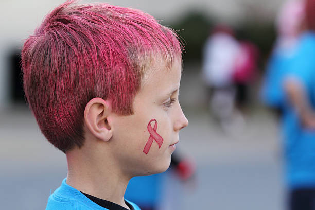 Boy with pink hair and breast cancer awareness ribbon stock photo