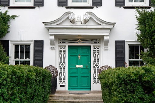 Front door of white stucco house with shrubbery