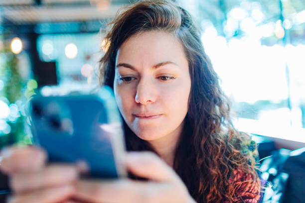 istock Young adult beautiful woman using mobile at cafe 1554034853
