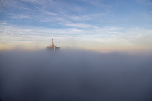 Toronto, Canada – October 13, 2022: The top of apartment buildings during sunrise surrounded by dense morning fog in Toronto