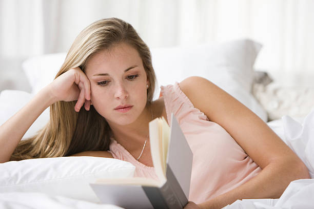 istock Beautiful young woman reading a book on bed 155403805