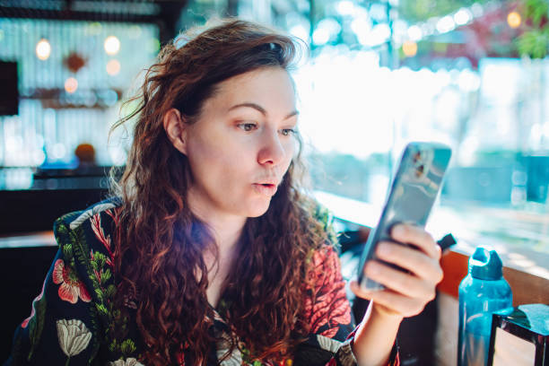 istock Young adult beautiful woman using mobile at cafe 1554038465