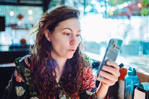Young adult woman using mobile at cafe