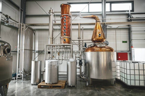 modern alcohol distillery equipment in manufacturing. industrial equipment for whisky production. - assemblagelijn fotos stockfoto's en -beelden
