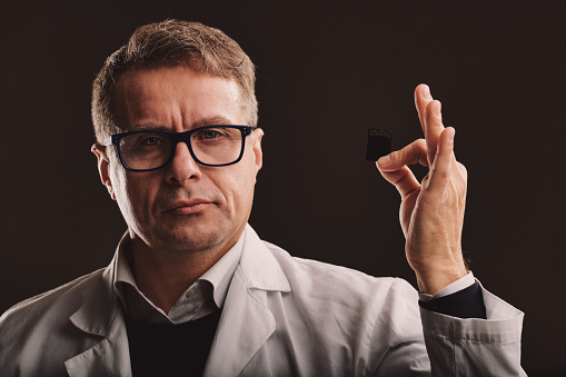 A now vintage image of a middle-aged computer scientist in a lab coat holding an SD card as if it's the latest state-of-the-art technology, looking at you with utmost conviction. Miniaturization can't
