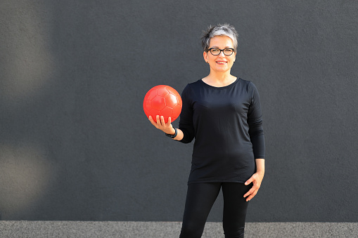 Modern mature woman with a ball in her hands, active lifestyle.