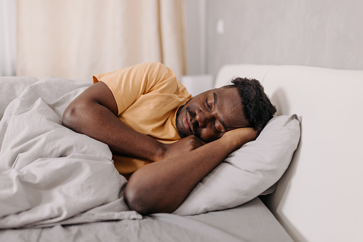 Finding tranquility and restfulness in his morning slumber, this young man of African American descent embraces the serenity of the early hours, allowing his body and mind to recharge for the day ahead