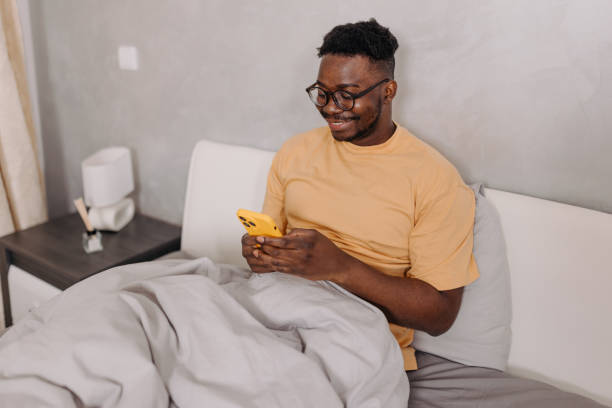 istock Young man wakes up and immediately reaches for his phone, staying connected even before leaving his bed 1554073261