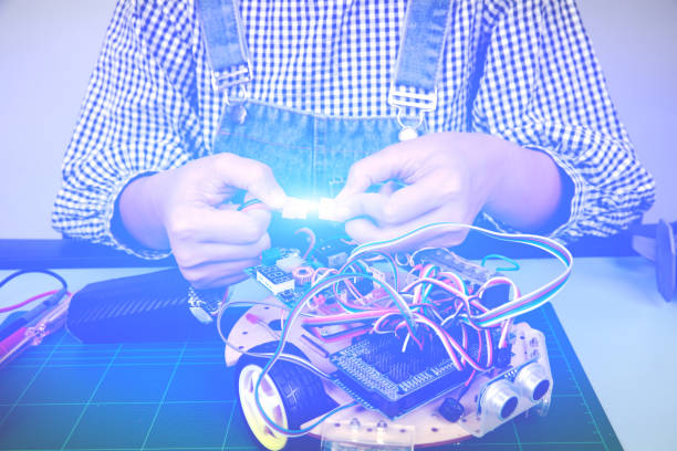 istock Female student assembly power cable of the robot, Engineer research robot, Close up hand plug in the robot learning set 1554074342