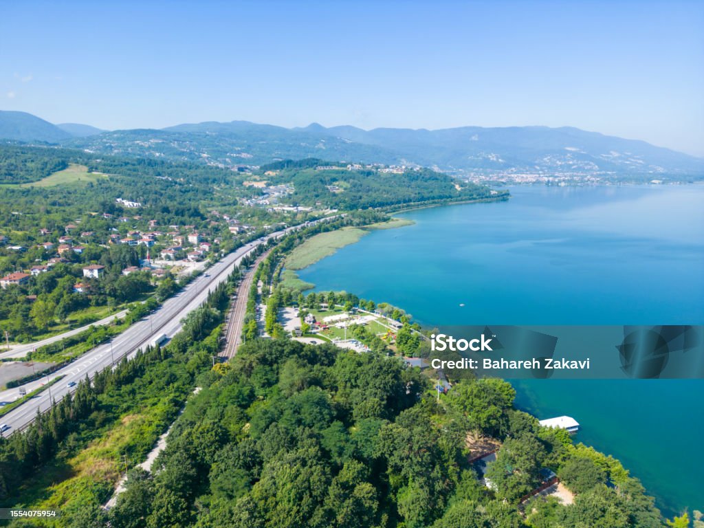 Aerial view with drone of highway road near the Sapanca Lake, Sakarya, Turkey Heavy car and truck traffic on rural highway among green forests and lake, aerial view. Türkiye - Country Stock Photo