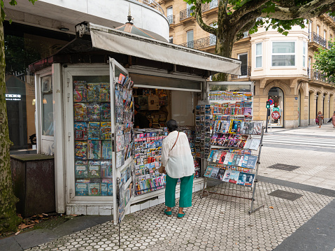 Customer at news and magazine stand - newspaper street kiosk. San Sebastian, Spain - July 11, 2023
