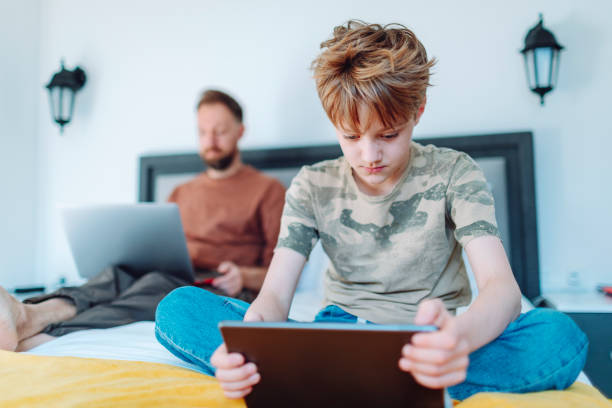 istock Father working from home using laptop with his son using digital tablet nearby 1554079523
