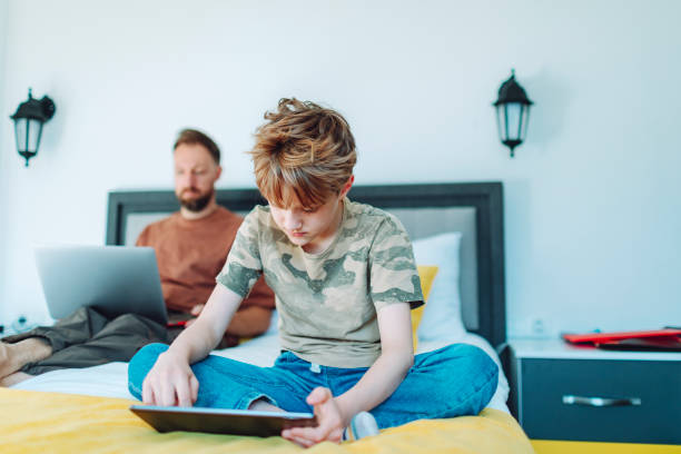 istock Father working from home using laptop with his son using digital tablet nearby 1554080711