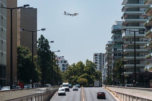 Lisbon, Portugal - July 18, 2023: View of a TAP aircraft flying over a busy highway in Lisbon, Portugal on the way to land at the airport