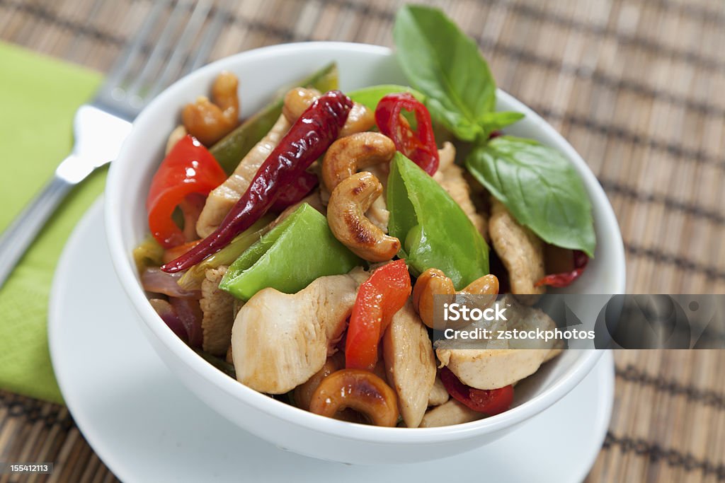 Chicken cashew nuts Chicken with cashew nuts, chili, peas, capsicum on a bamboo mat with fork Cashew Stock Photo