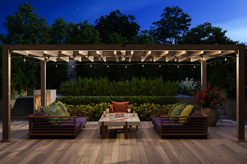 Modern Patio With Sofa, Armchair, Coffee Table And Garden View Background At Night