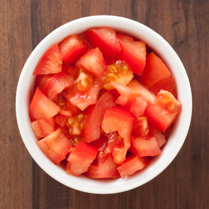 Top view of white bowl full of diced tomato