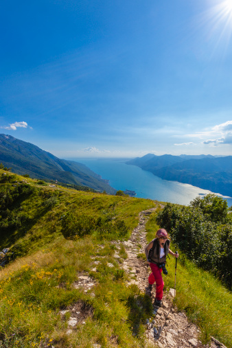Woman walking on a footpath on Monte Baldo, a mountain in the Italian Alps with a ridge that stretches for 40 km parallel to the Lake Garda. Monte Baldo reaches the maximum elevation of 2,218 m with the Valdritta, and the minimum elevation of 65 m on Lake Garda. Monte Baldo, Italy. -blurred motion-