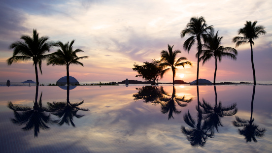 The sun sets over the ocean and an infinity pool in Mexico.