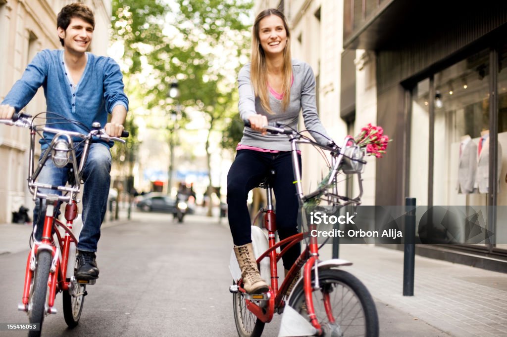 Pareja montando una bicicleta en la ciudad - Foto de stock de Andar en bicicleta libre de derechos