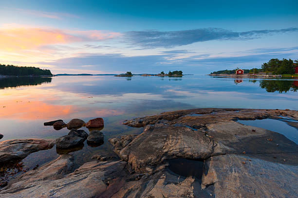 Sunset in the archipelago Sunset in the Swedish archipelago. A typical red cottage is mirrored in the calm water. archipelago stock pictures, royalty-free photos & images