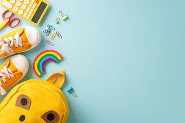 istock Growing curious minds. Creative top view of a cute children's backpack filled with lively school essentials and sneakers on a pastel blue backdrop, perfect for text or promotional content 1554166514