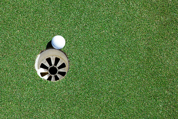 istock Golf ball teetering by the whole on the green 155417828