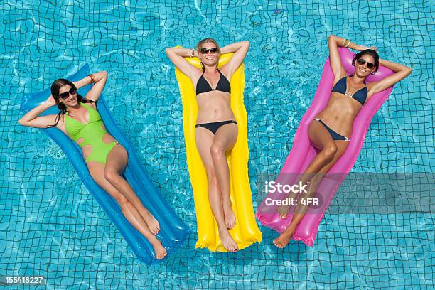 Foto de Três Mulheres Bonitas Tomando Sol Na Piscina e mais fotos de stock de Colchão de ar