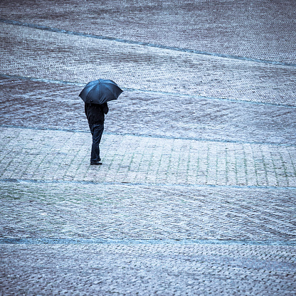 Lonely man standing with umbrella under the rain in Piazza del Campo, Siena, Tuscany.