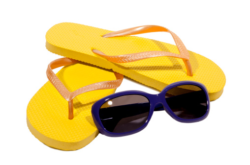 Great shot of yellow thongs(flip flops) and sunglasses ready to put on and wear for the summer.  Isolated on white with some small shadows around the thongs.