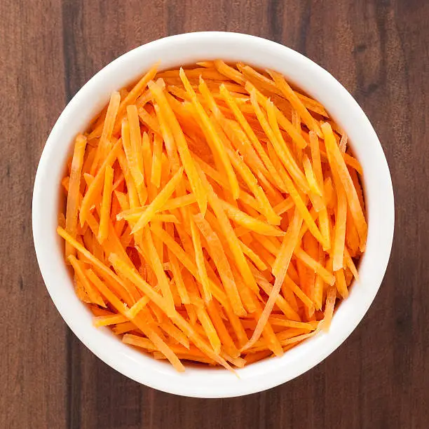 Top view of white bowl full of grated carrot