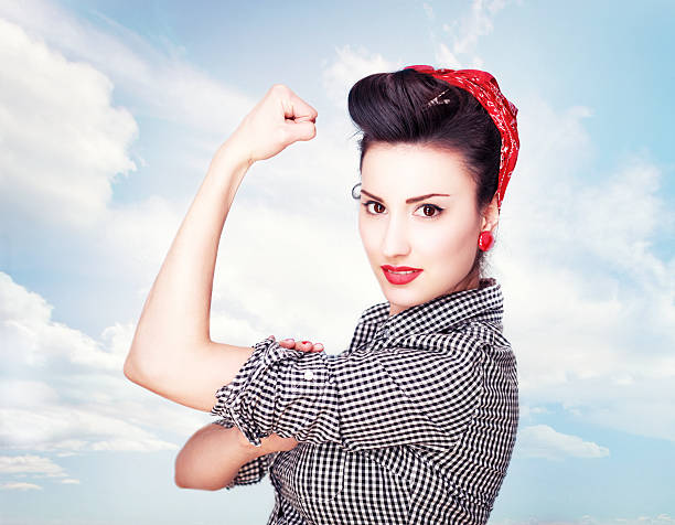 Brunette striking a famous Rosie Riveter pose Retro style portrait of a young brunette in vintage clothes, striking a famous WW2 Rosie the Riveter pose, expressing vitality, courange and determination.  rolled up sleeves stock pictures, royalty-free photos & images