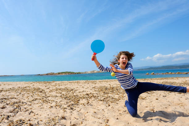 Actionshot of a happy young girl playing beach tennis. Location: La Tonnara Beach, Island of Corsica, France.