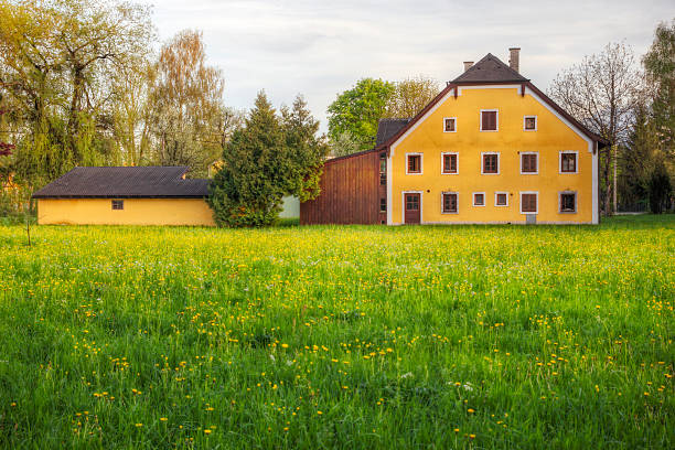 A charming and picturesque red house, beautifully set against a stunning green landscape underneath a clear blue sky