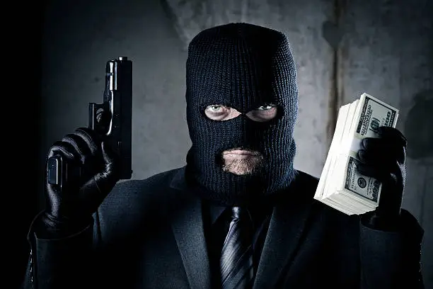 Criminal holding gun and stack of money