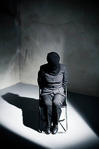 Prisoner tied to chair in cell spotlight Woman prisoner torture photos stock pictures, royalty-free photos & images