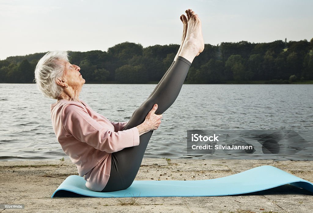senior woman exercising outdoors senior woman, 88 years old, very active and flexible, exercising  at a lake at a sunny summer morning,  Senior Adult Stock Photo