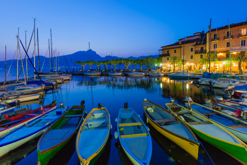 A row of fishing boats are lined in the small harbor of Torri del Benaco, . a tiny village of extraordinary charm with pretty houses painted in pastel colours and flowered balconies. It is located on the Veronese shore of Lake Garda, the largest Italian lake.