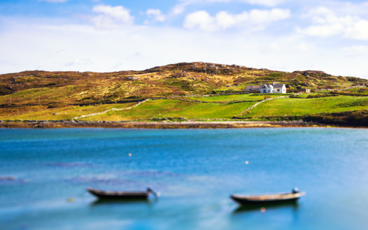 A white house on a hill with two boats in the sea. Tilt shift lens.