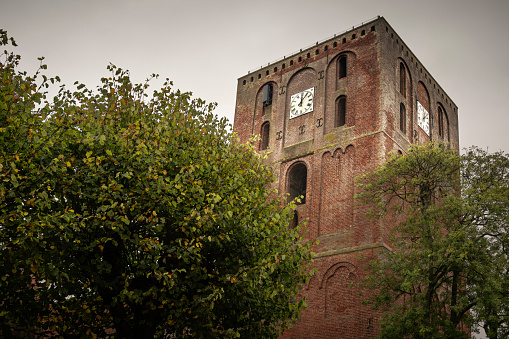 Marienhafe, Germany - October 13, 2022: The Stoertebekerturm on a rainy day in autumn. The story goes that the pirate Klaus Stoertebeker sought refuge in the port of Marienhafe at the end of the 14th century. At that time, fleeing from the Hanseatic League, Denmark and the German Order of Knights, the pirates Klaus Stoertebeker and Goedeke Michel fled with other pirates to Marienhafe, which was located directly on the North Sea after a heavy storm surge.