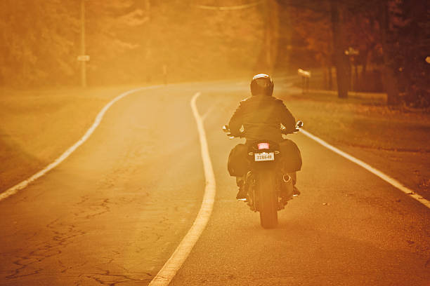 Biker touring during a lovely Fall morning.  Short depth of field. Shot with 5DII, real lens flare. Fake license plate number.