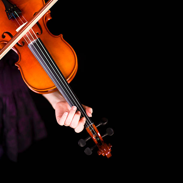 Young girl practicing the violin. Over black background. stock photo